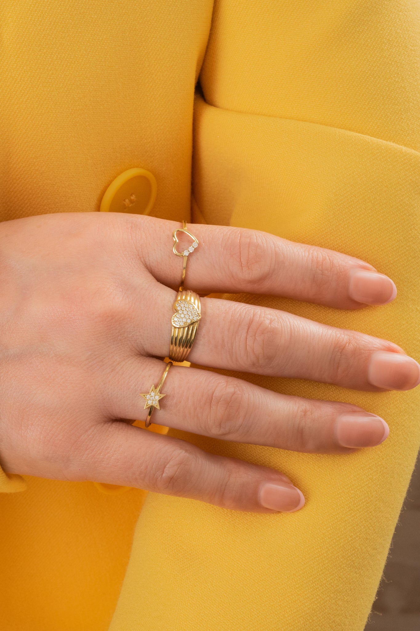 Anillo de oro solido en 10 kilates con un controno de seis lineas lisas delgadas con un corazón en el centro de zirconias