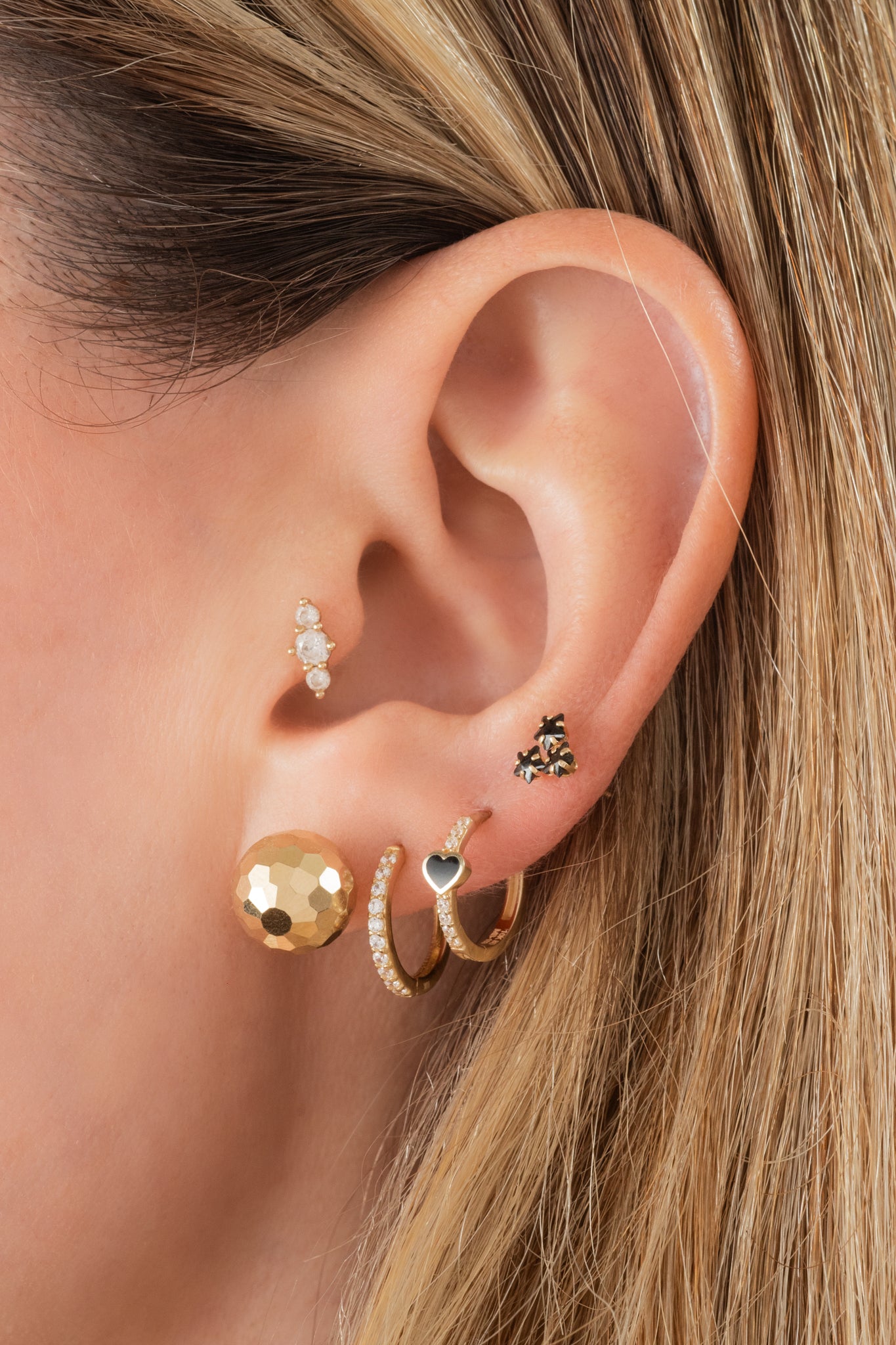 Huggie de oro solido en 10 kilates con un corazón negro en el centro y zirconia al rededor