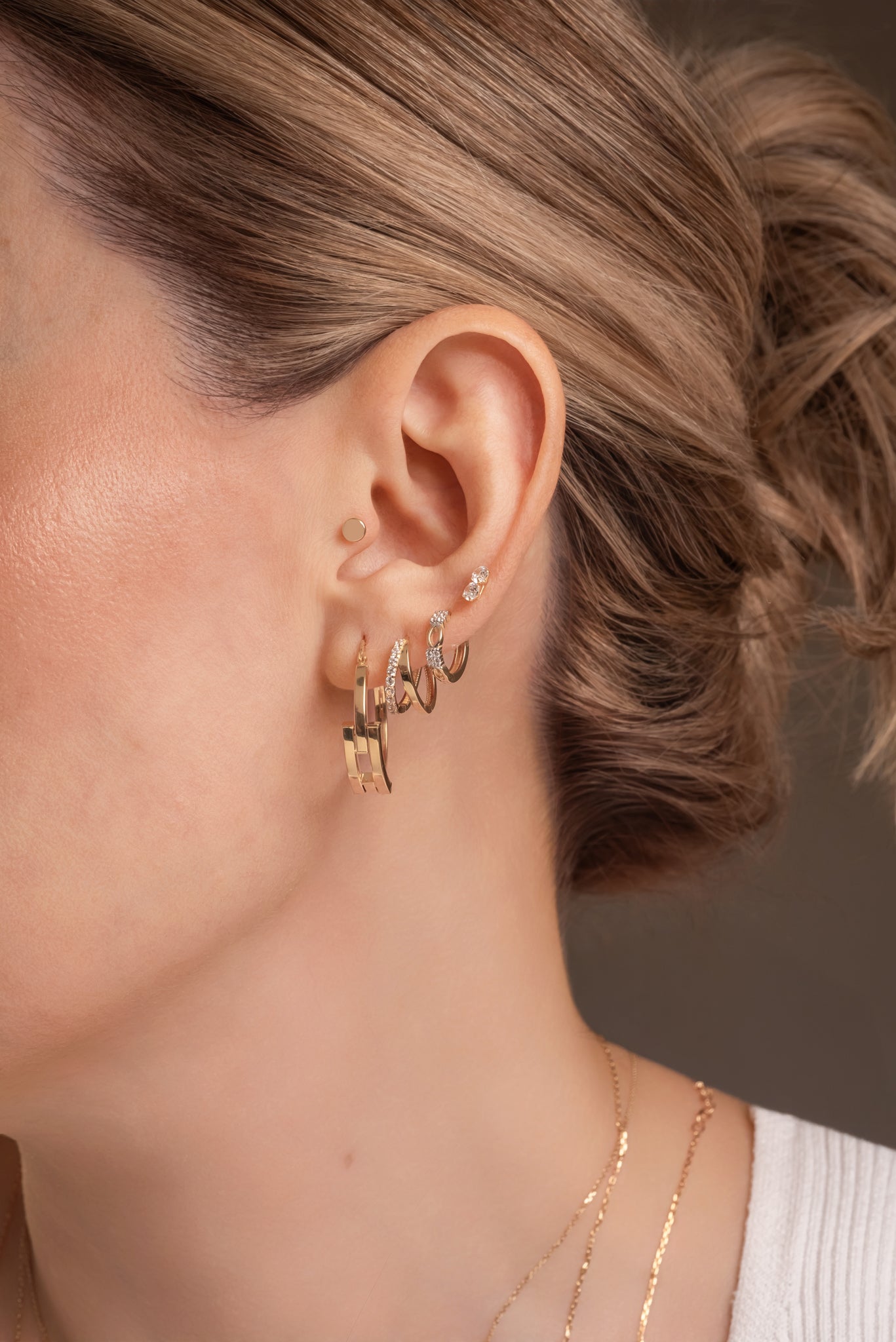 Huggie de oro sólido en 14 kilates con cuadro de zirconias y óvalos huecos lisos.