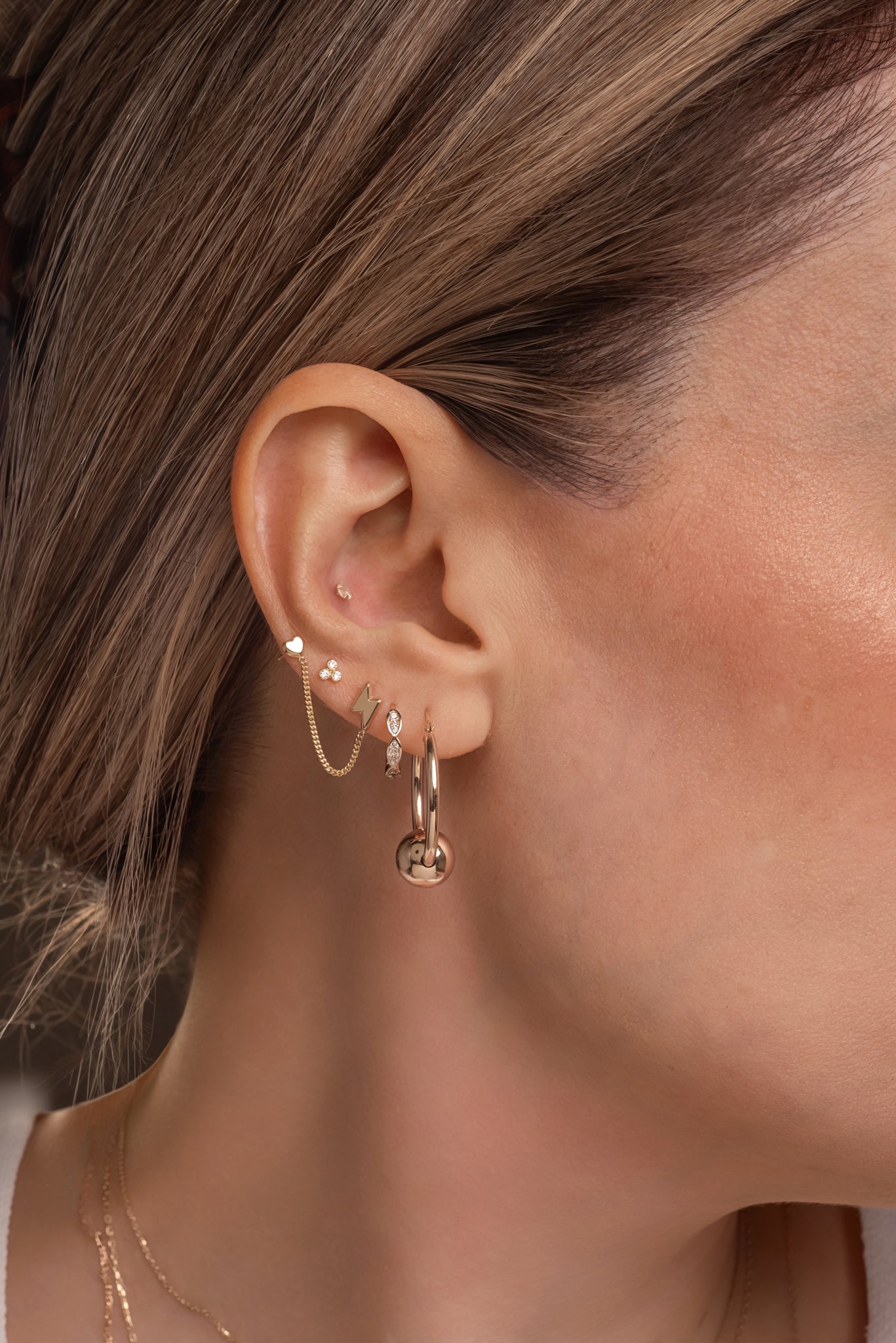 Huggie de oro sólido en 14 kilates con formas de semillas tupidas de zirconias.