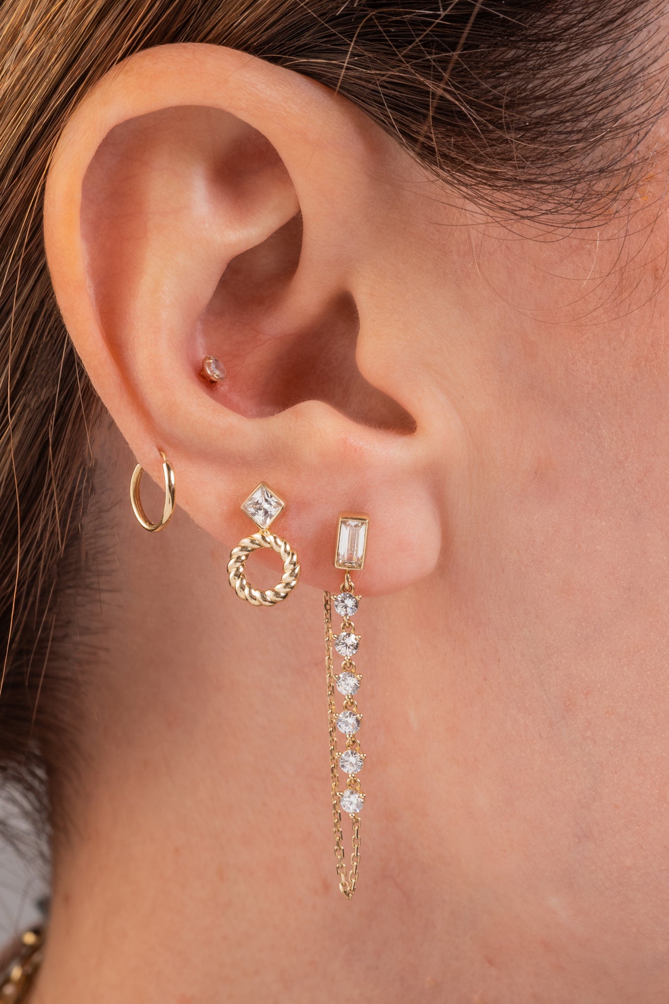 Arete de oro sólido en 10 kilates con rombo biselado y aro trenzado liso debajo.