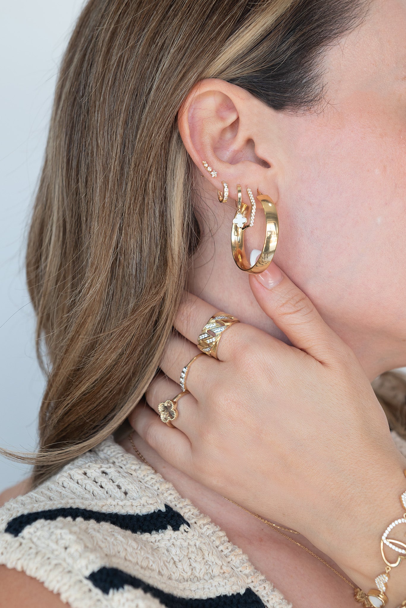 Huggie 10 kilates flor de cuatro pétalos con esmaltado blanco.