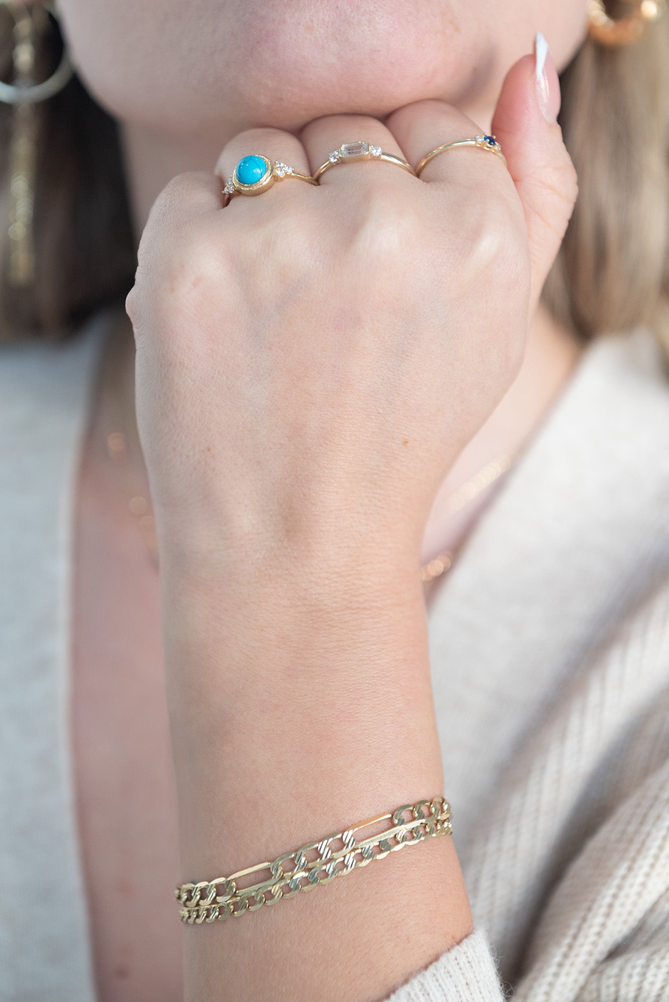 Anillo 14 kilates con brazo fino y centro piedra turquesa circular y tresillo zirconias laterales.