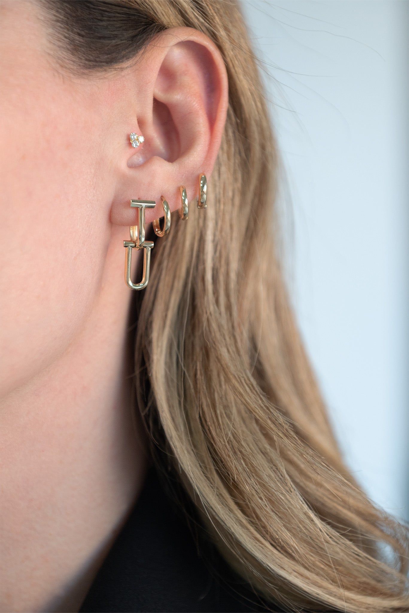 Arracada 10 kilates forma de T con dije de U.