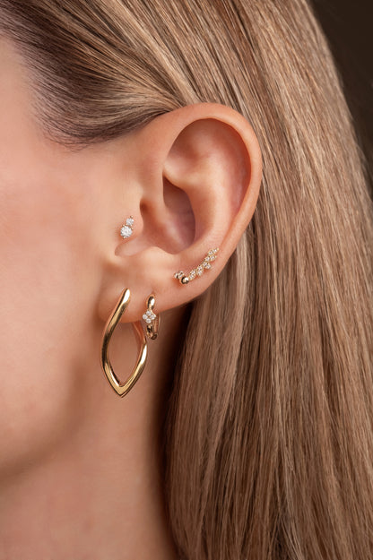 Huggie de oro sólido en 14 kilates con flor de cuatro pétalos mini de zirconias.