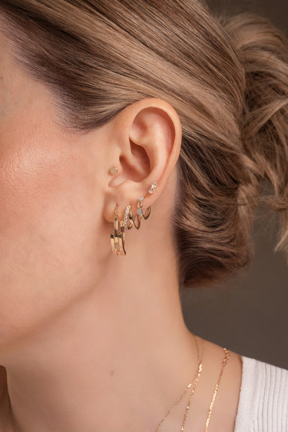 Huggie de oro sólido en 14 kilates con cuadro de zirconias y óvalos huecos lisos.