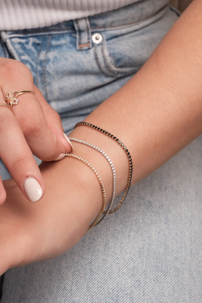 Pulsera tenis de oro sólido en 14 kilates con zirconias negras montadas en oro amarillo.