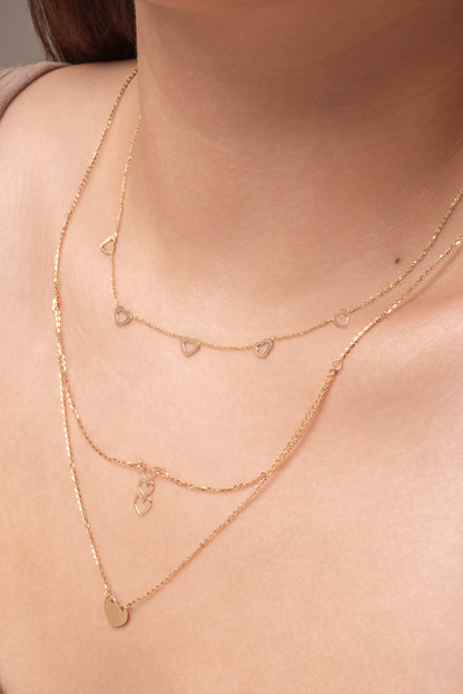 Gargantilla de oro sólido en 10 kilates con dijes de corazones contorno hueco.