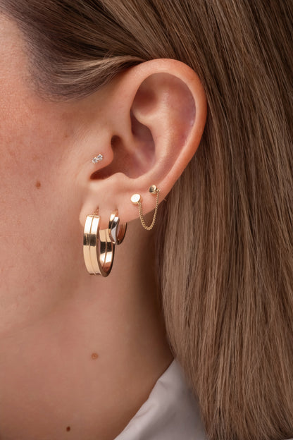 Huggie de oro sólido en 14 kilates con doble hilera oro blanco y oro amarillo.