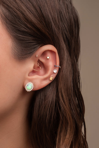 Arete en 14 kilates con un ópalo en el centro con zirconia alrededor en pico.