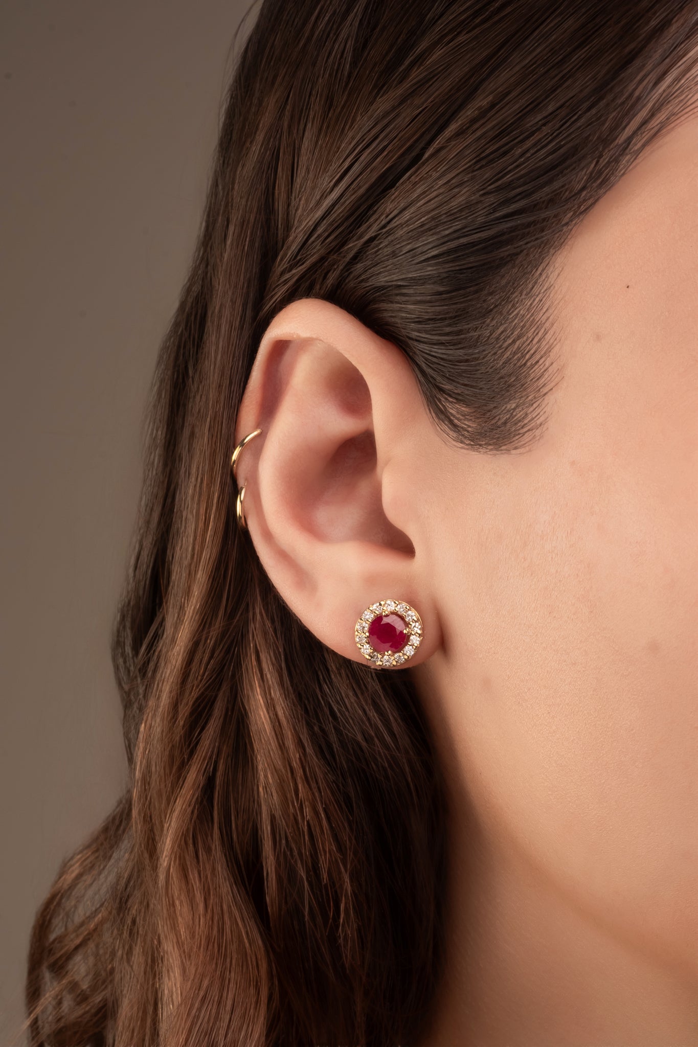 Arete en 14 kilates con un corte circular con rubí en el centro y alrededor brillantes.