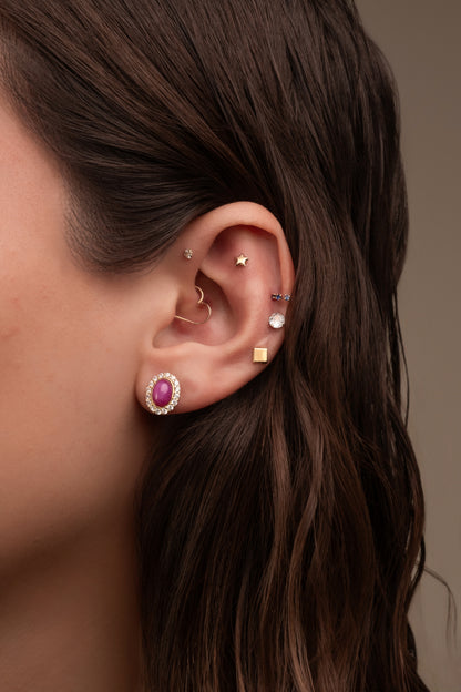 Arete en 14 kilates con un corte de uva con rubí estrella con zirconia alrededor.