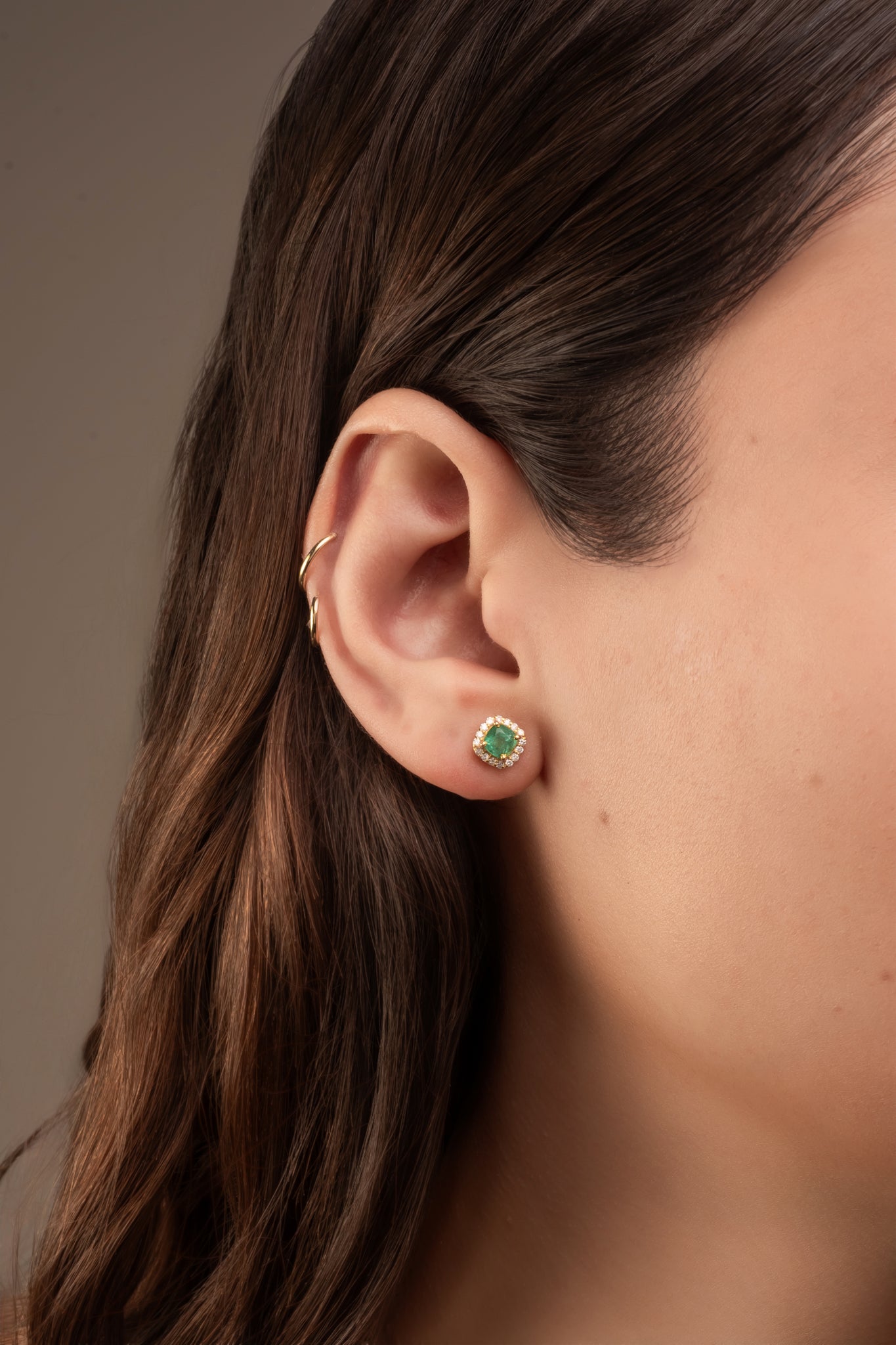 Arete en 14 kilates con corte cuadrado chico con una esmeralda en el centro circular con un contorno de brillantes.