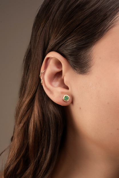 Arete en 14 kilates con corte cuadrado chico con una esmeralda en el centro circular con un contorno de brillantes.