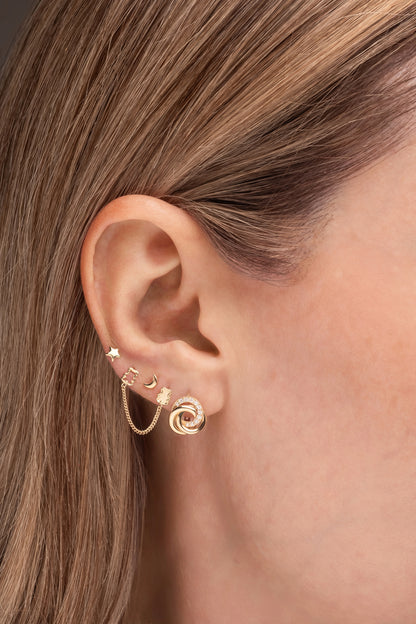 Huggie de oro sólido en 14 kilates con tres aros enlazados, dos lisos y uno con zirconias.