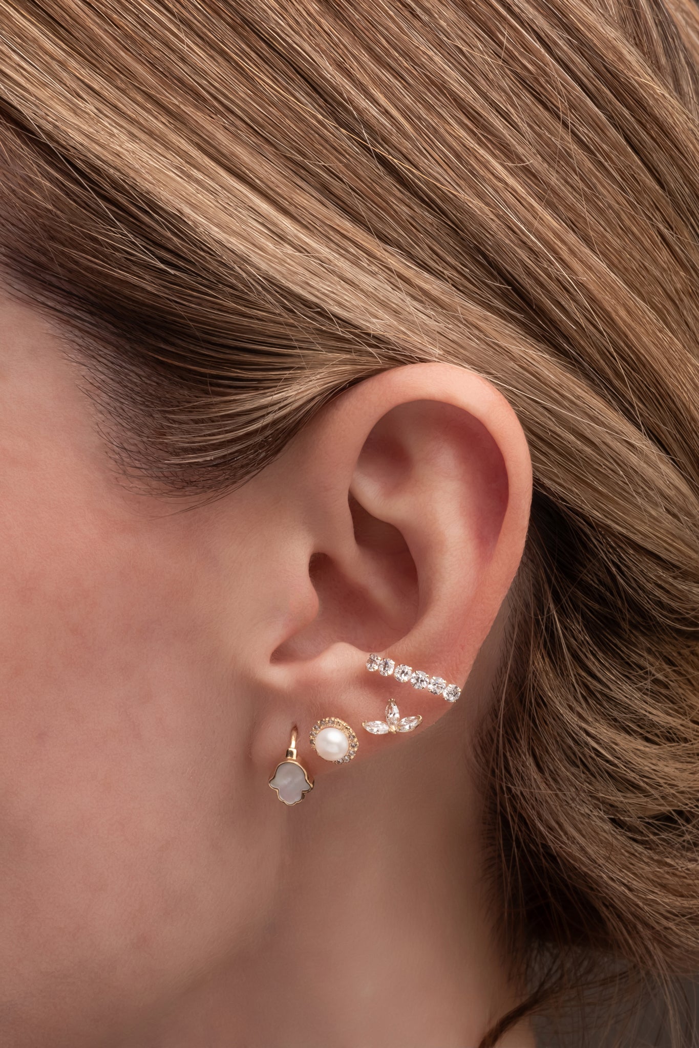 Huggie de oro sólido en 14 kilates con mano de fátima madre perla.