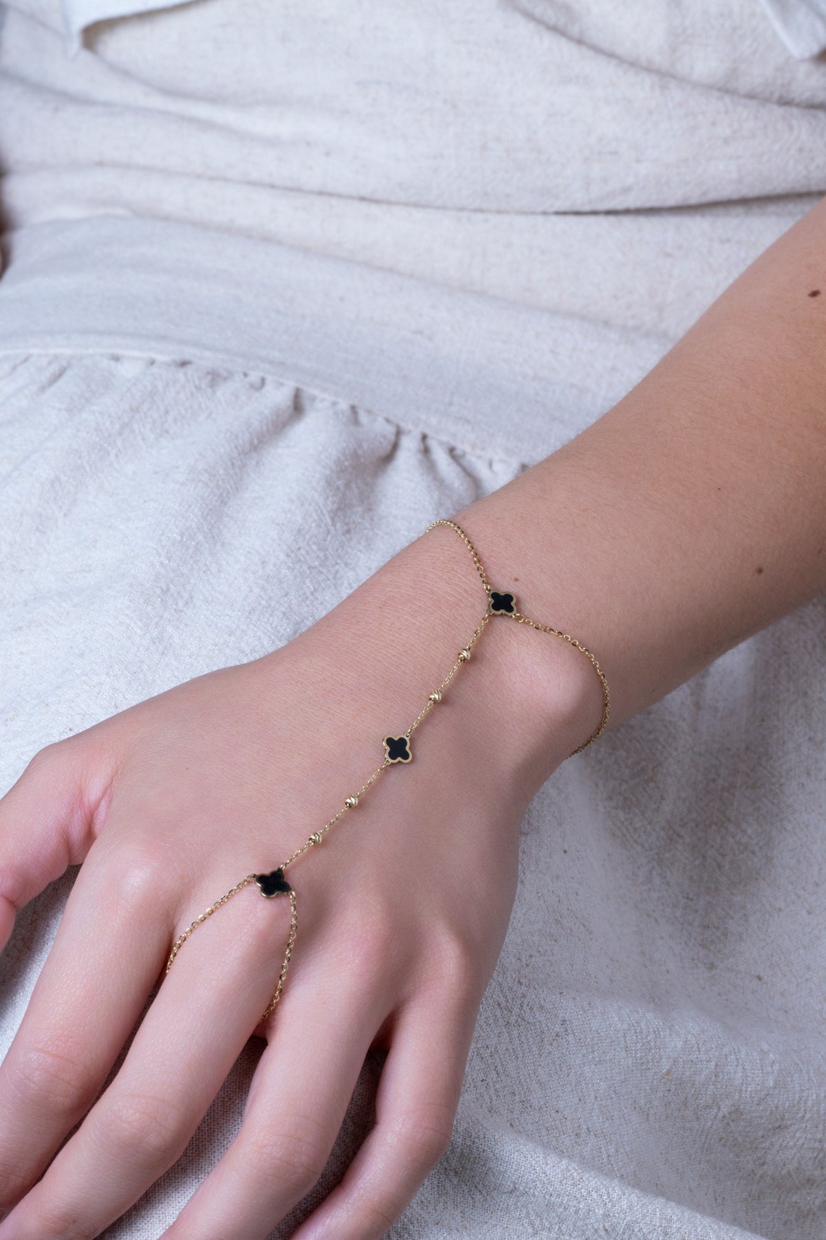 Pulsera handchain 10 kilates flores negras y bolitas.
