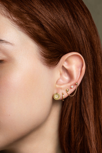 Arete 10 kilates círculo de zirconias y contorno liso con letras.